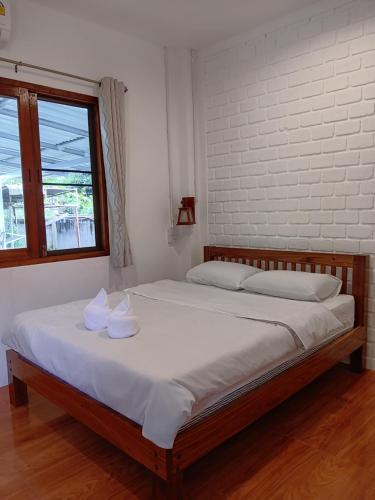 a bedroom with a bed with white sheets and a window at Baankanoonpai(บ้านขนุนปาย)​ in Pai