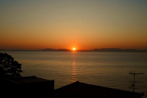 a sunset over a body of water at 海に恋する泊まれる喫茶店 ポパイ in Iyo