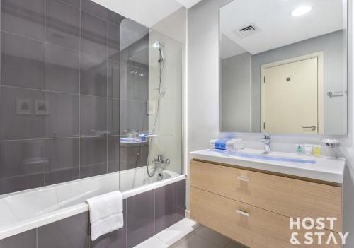 een badkamer met een bad, een wastafel en een douche bij Studio in Golf Vista, Damac Hills - Host & Stay in Dubai