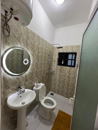 uma casa de banho com um lavatório, um WC e um espelho. em Cosy Verve em Lomé