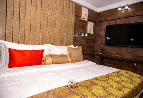 1 dormitorio con 1 cama blanca grande con almohadas coloridas en Joker Hotel and Suites, en Benin City