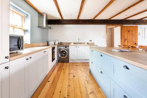 una cucina con armadietti bianchi e lavatrice di Large converted barn in peaceful, rural location a Hambleton