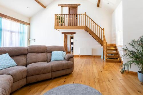 a living room with a couch and a staircase at Large converted barn in peaceful, rural location in Hambleton