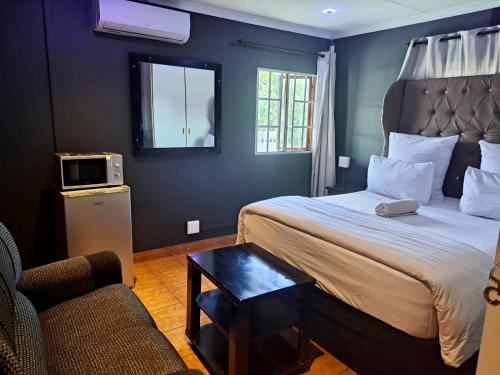 Habitación de hotel con cama y silla en Mino Guest House, en Pietermaritzburg