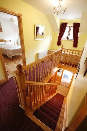eine Holztreppe in einem Zimmer mit einem Schlafzimmer in der Unterkunft Macreddin Rock Bed & Breakfast in Aughrim