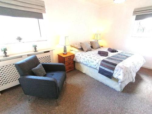 um quarto com uma cama, uma cadeira e uma janela em Cartref Bach em Llanybyther