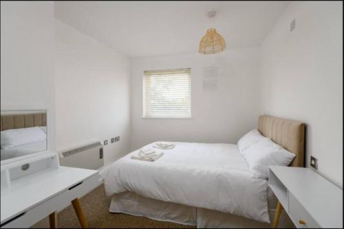 a white bedroom with a bed and a sink at Modern 2 Bedroom Flat with Parking in Cardiff in Cardiff