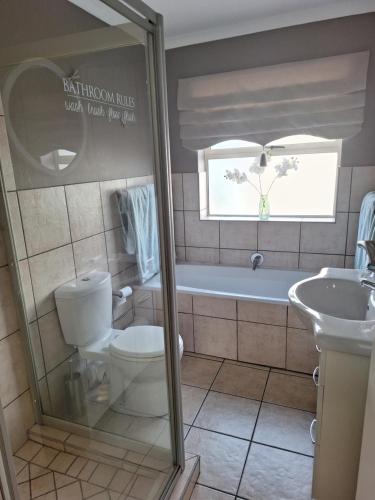 a bathroom with a tub and a toilet and a sink at Estoril Villas 10 in Mossel Bay