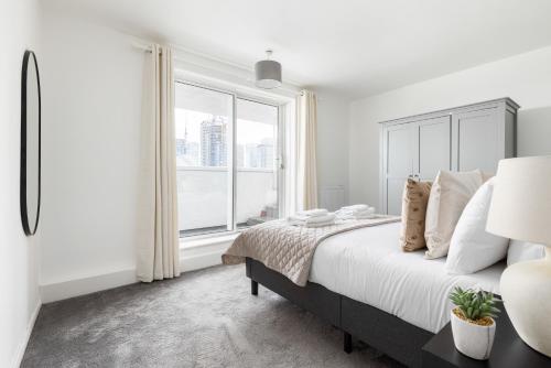 a bedroom with a large bed and a large window at The Canary Wharf Collection in London