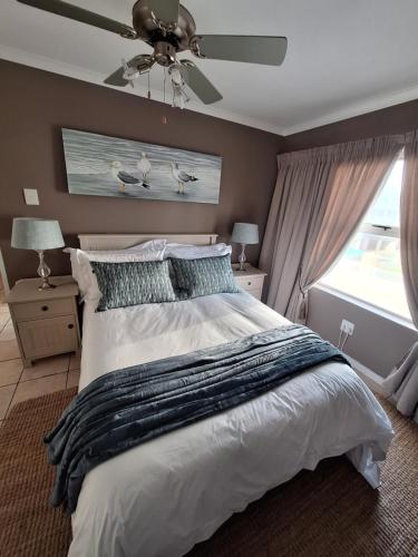 a bedroom with a large bed with a ceiling fan at Estoril Villas 10 in Mossel Bay
