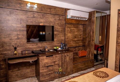 ein Hotelzimmer mit einem TV an einer Holzwand in der Unterkunft Joker Hotel and Suites in Benin-Stadt