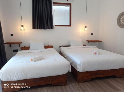 2 bedden in een kamer met witte lakens bij Sekar Kuning Bungalows in Kuta Lombok
