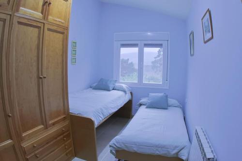 a small room with two beds and a window at Casa el Cerezo Rojo in El Rasillo