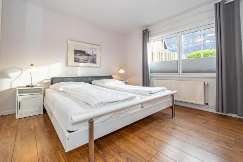 ein Schlafzimmer mit einem weißen Bett und einem großen Fenster in der Unterkunft Strandberg III in Westerland