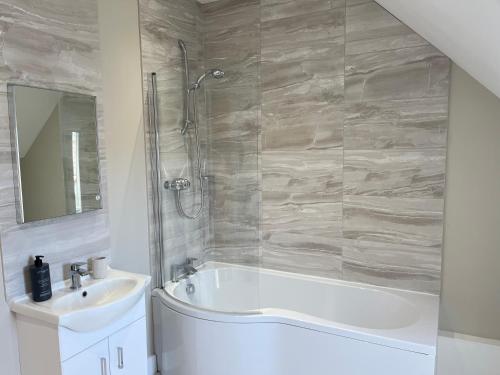 a bathroom with a bath tub and a sink at Honeysuckle Barn, Martham in Great Yarmouth