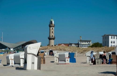 ein Leuchtturm am Strand mit Stühlen und einem Leuchtturm in der Unterkunft Birnbom Warnemünde in Warnemünde