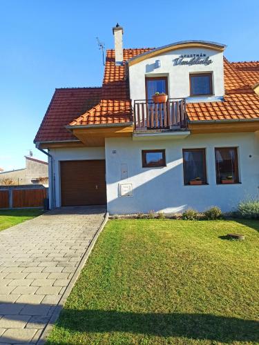 a white house with a balcony and a yard at Apartmán Vendelínka in Valtice