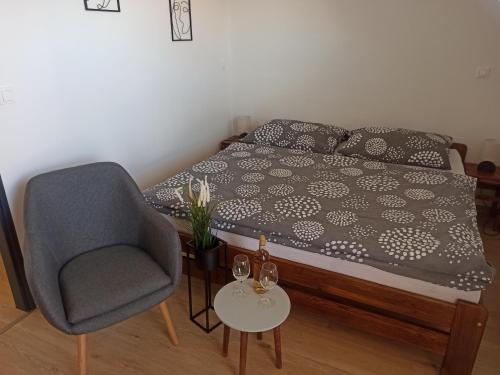 a bedroom with a bed and a chair and a table at Apartmán Vendelínka in Valtice