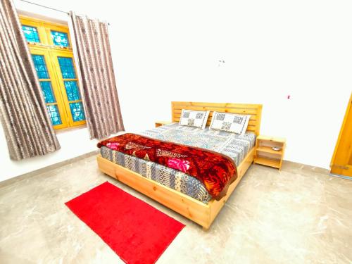 a bedroom with a bed and a red rug at Travelodge Homestay in Bīr