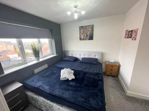 um quarto com uma cama com um cobertor azul e uma janela em New beautiful house in a perfect location em Newcastle under Lyme