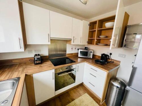 una pequeña cocina con armarios blancos y microondas en New beautiful house in a perfect location, en Newcastle-under-Lyme