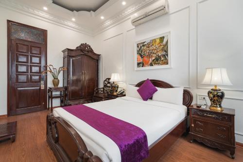 a bedroom with a large white bed with purple sheets at Hanoi Little Town Hotel in Hanoi