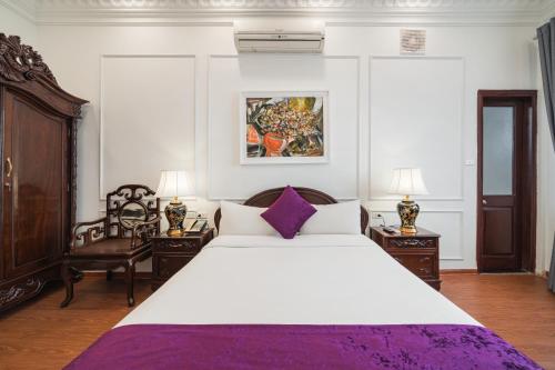 a bedroom with a large white bed and two chairs at Hanoi Little Town Hotel in Hanoi
