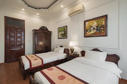 a hotel room with two beds and a painting on the wall at Hanoi Little Town Hotel in Hanoi