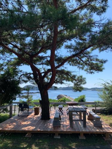 a wooden deck with a tree and a picnic table at 大砂荘 OZUNA CAMP and LODGE in Kaiyo