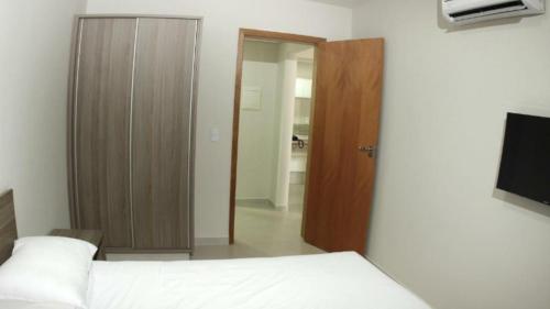 een slaapkamer met een bed en een deur naar een badkamer bij Atrium Flat in Caldas Novas