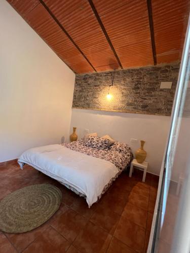 a bedroom with a bed and a stone wall at La casa de las piedras 