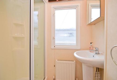 ein Bad mit einem Waschbecken, einem Fenster und einer Dusche in der Unterkunft KINSGATE 2 in Shanklin