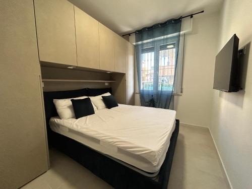 1 dormitorio con 1 cama con sábanas y almohadas blancas en Appartamento Conchiglia-Immobili e Soluzioni Rent, en Lido Adriano