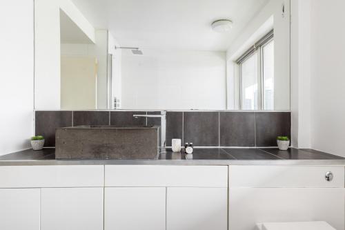 a white bathroom with a sink and a mirror at The Canary Wharf Collection in London