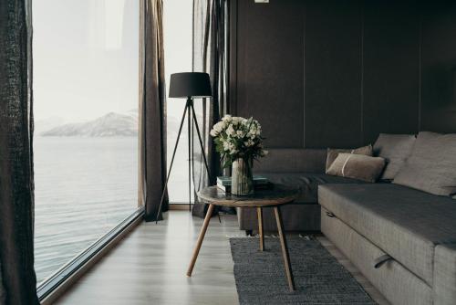 a living room with a couch and a table with flowers at Aurora Fjord Cabins in Lyngseidet