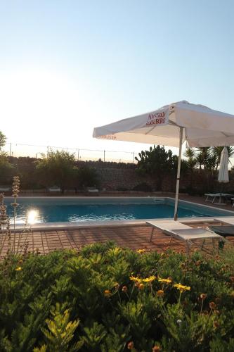 a pool with an umbrella and a chair and a table at Agriturismo Masseria Alberotanza in Conversano