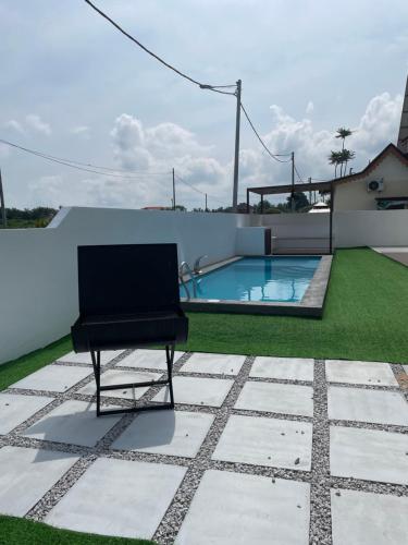 a chair sitting on a patio with a swimming pool at Traditional Melaka Homestay with Private Pool in Kampong Bukit Katil