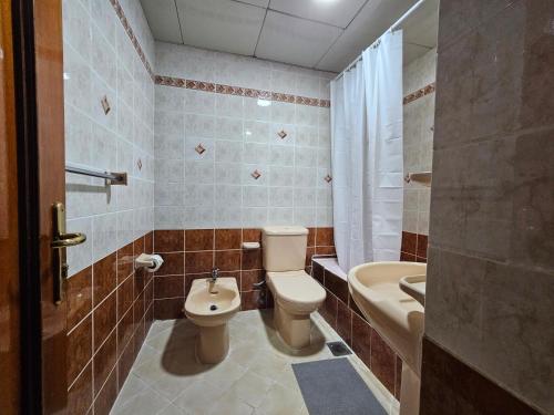 uma casa de banho com um WC, um lavatório e uma banheira em Oasis Hostel em Abu Dhabi