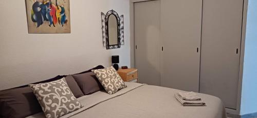 een slaapkamer met een bed met kussens en een spiegel bij Plein centre, proche plage et port, garage in Águilas