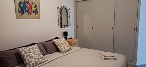 Un dormitorio con una cama con almohadas y un espejo. en Mawilec, centre, plage, port, garage, en Águilas