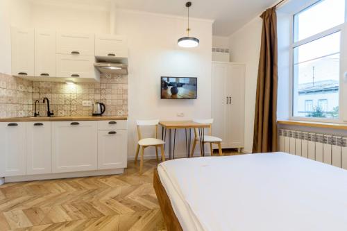 a bedroom with a bed and a kitchen with a table at Idea Design Apart-Hotel Chykalenka in Kyiv