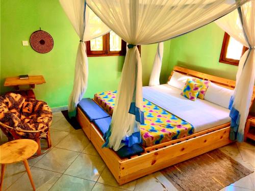 a bedroom with a bed with a canopy and a chair at Airport Link Guest House in Entebbe