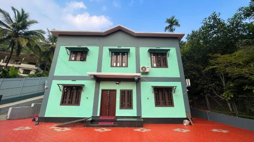 una pequeña casa verde con suelo rojo en Welldone Wayanad Holidays en Sultans Battery