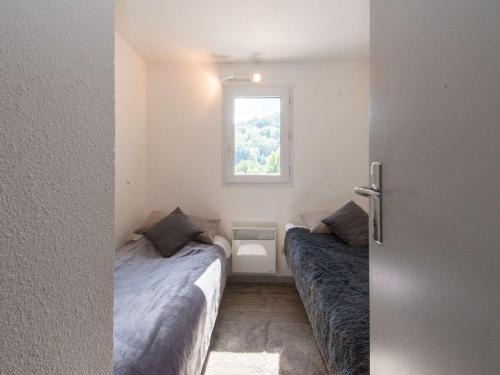 une petite chambre avec deux lits et une fenêtre dans l'établissement Appartement cosy 6 pers, centre Saint-Lary, balcon sud, parking, 2 chambres, classé 2 étoiles - FR-1-296-142, à Saint-Lary-Soulan