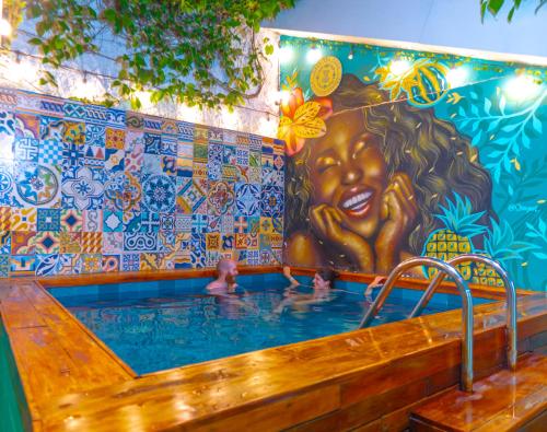 una piscina con gente con un mural en Casa Del Pozo Boutique Hostel en Cartagena de Indias