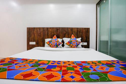 a bed with a colorful blanket on top of it at FabHotel Krishna Inn in Bhiwandi