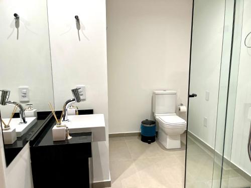 a bathroom with a toilet and two sinks and a shower at Studio moderno a 5min a pé do Allianz Parque in Sao Paulo