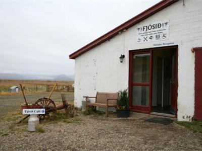 a white building with a red door and a bench at Guesthouse Holmur in Hólmur