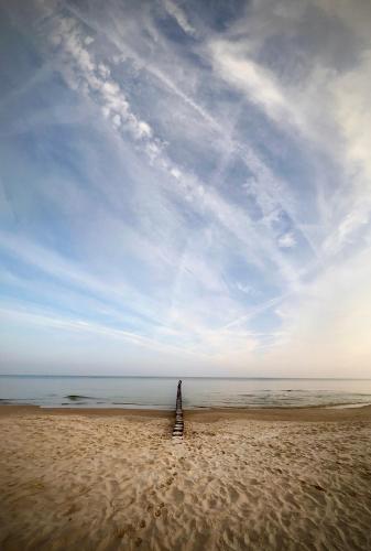 a person standing on a beach with the ocean at Apartamenty Mesa Grill Restaurant Cafe in Dźwirzyno