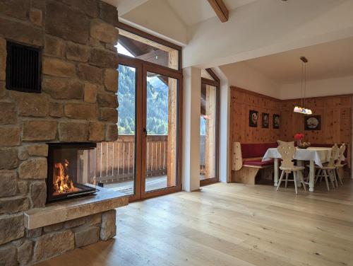 a living room with a stone fireplace and a dining room with a table at ARLhome Lodge - Zuhause am Arlberg in Sankt Anton am Arlberg